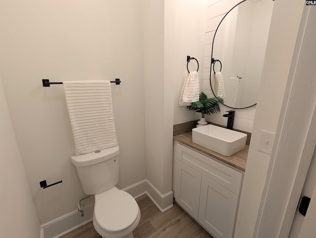 bathroom with baseboards, wood finished floors, toilet, and vanity