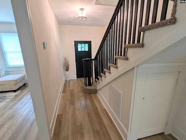 foyer entrance with wood finished floors, stairs, and baseboards