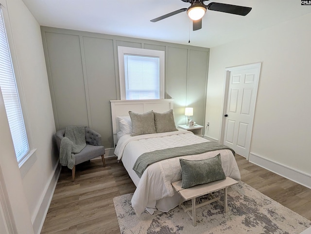 bedroom with multiple windows, wood finished floors, baseboards, and ceiling fan