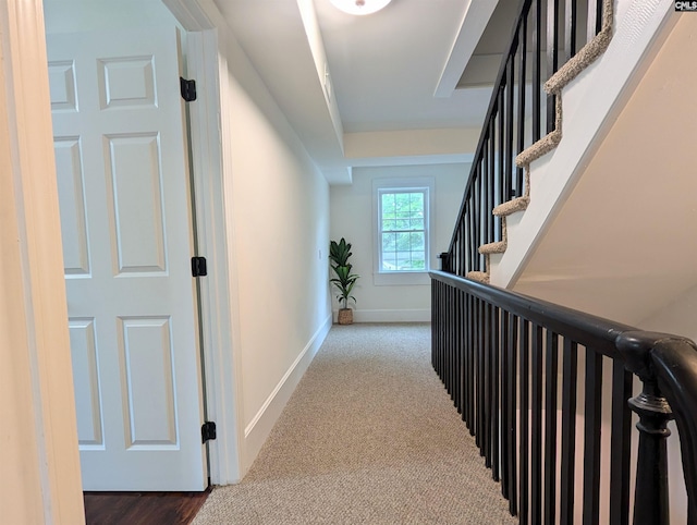corridor with baseboards, stairway, and carpet flooring