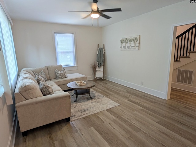 living room with stairway, wood finished floors, a ceiling fan, and baseboards