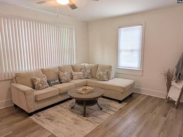 living room with a ceiling fan, baseboards, and wood finished floors