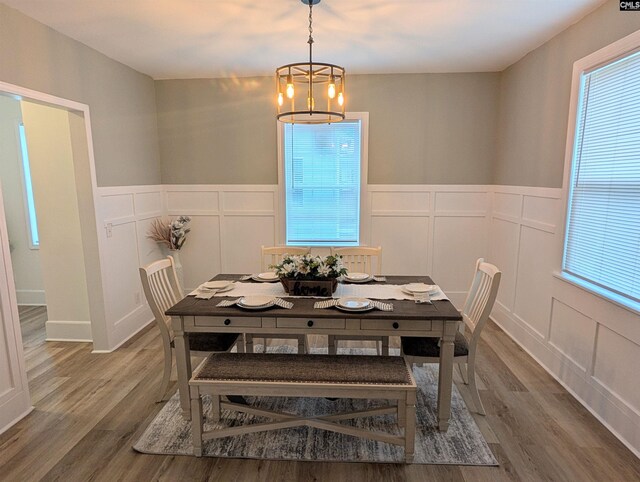 dining room with a decorative wall, wood finished floors, wainscoting, and a chandelier