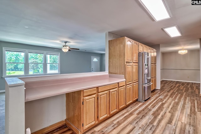 kitchen with high quality fridge, light countertops, light wood-style flooring, a peninsula, and a ceiling fan