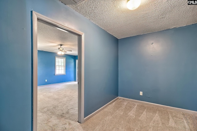 unfurnished room featuring a textured ceiling, carpet flooring, baseboards, and a ceiling fan