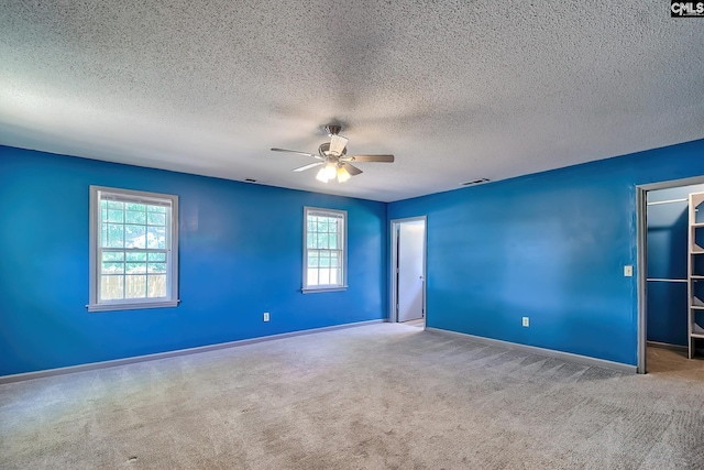 carpeted empty room with ceiling fan, baseboards, and a textured ceiling