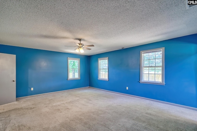 unfurnished room featuring healthy amount of natural light, carpet, ceiling fan, baseboards, and a textured ceiling