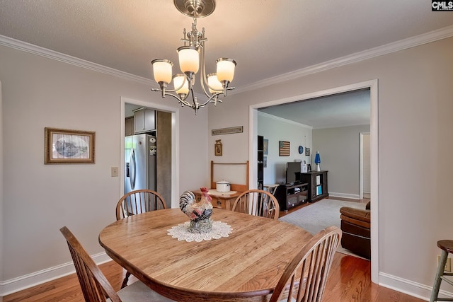 dining room featuring crown molding, a chandelier, light wood-type flooring, and baseboards