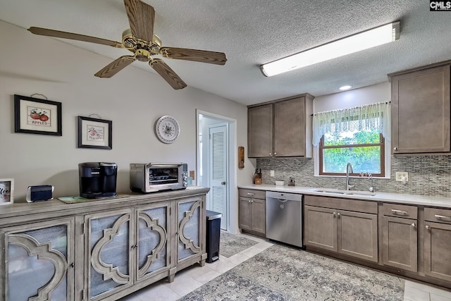 kitchen featuring a sink, stainless steel dishwasher, decorative backsplash, light tile patterned flooring, and a textured ceiling