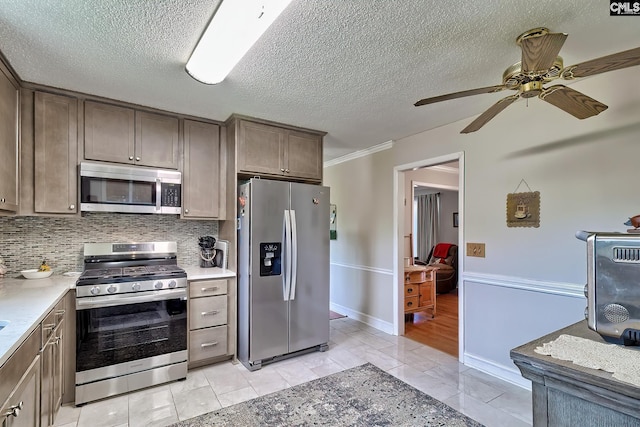 kitchen with stainless steel appliances, a ceiling fan, tasteful backsplash, light countertops, and a textured ceiling