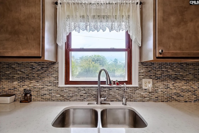 kitchen featuring a sink, tasteful backsplash, and light stone counters