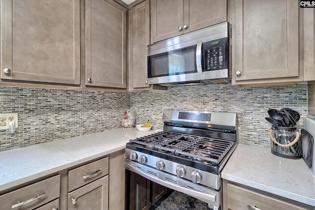 kitchen featuring stainless steel appliances, backsplash, and light stone countertops