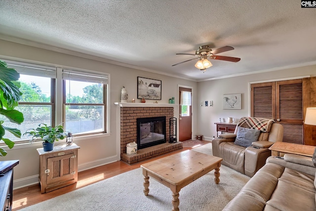 living room with plenty of natural light, ceiling fan, ornamental molding, a fireplace, and wood finished floors