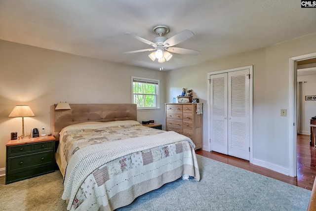 bedroom with a closet, wood finished floors, ceiling fan, and baseboards