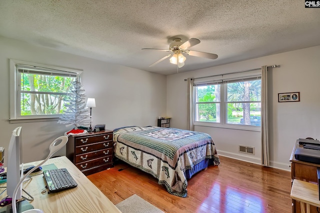 bedroom with wood finished floors, a textured ceiling, a ceiling fan, and baseboards