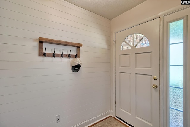 entryway featuring wooden walls and a textured ceiling