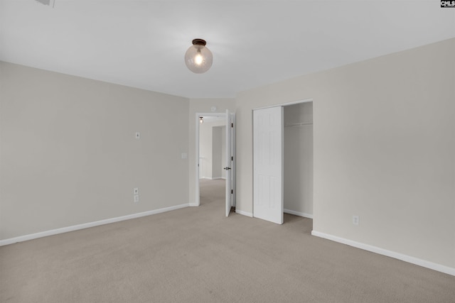 unfurnished bedroom with light colored carpet, baseboards, and a closet