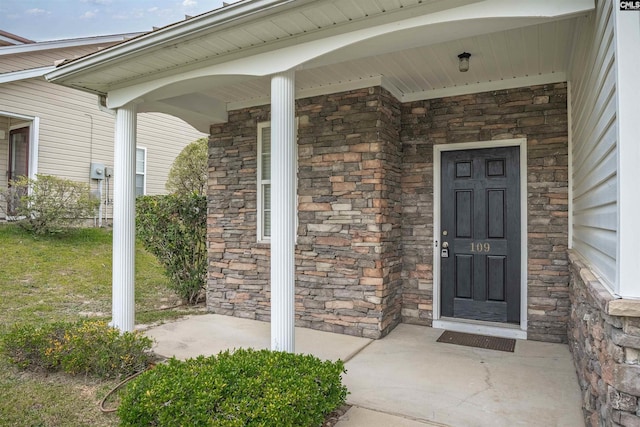 view of exterior entry with stone siding and covered porch