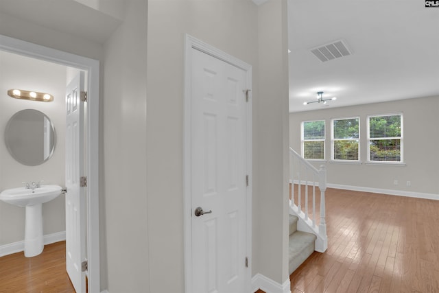 hall with light wood finished floors, baseboards, and stairway
