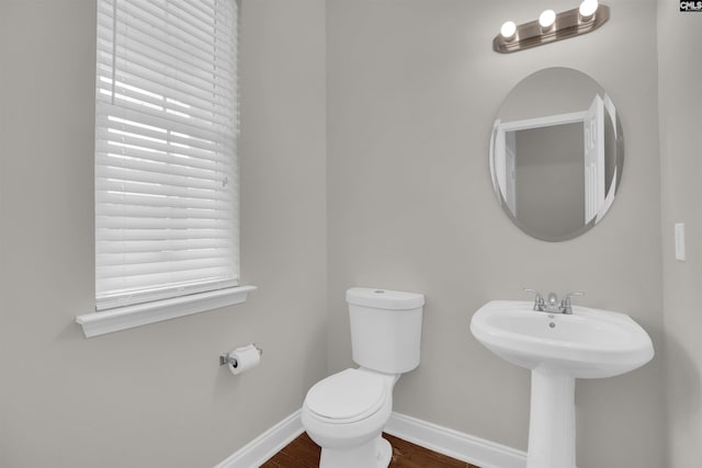 bathroom with toilet, baseboards, and wood finished floors