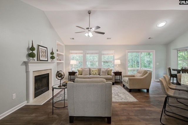 living room featuring lofted ceiling, ceiling fan, a tiled fireplace, dark wood finished floors, and baseboards