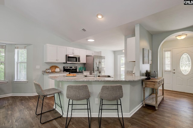 kitchen with stainless steel appliances, a breakfast bar area, a peninsula, white cabinets, and a sink