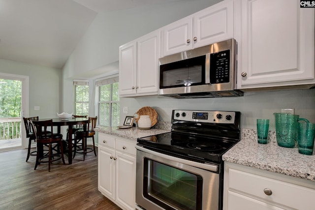 kitchen with appliances with stainless steel finishes, lofted ceiling, white cabinets, dark wood-style flooring, and light stone countertops