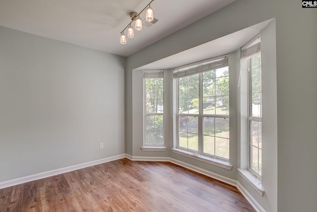 unfurnished room with plenty of natural light, baseboards, and wood finished floors