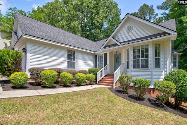 view of front facade with roof with shingles and a front yard