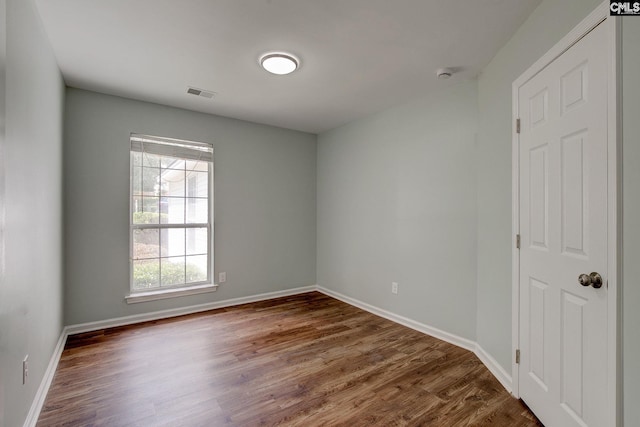 spare room featuring wood finished floors, baseboards, and a smoke detector