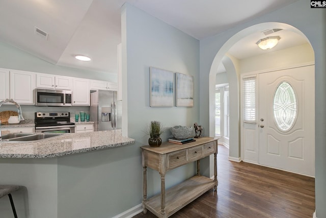 entrance foyer featuring arched walkways, dark wood finished floors, baseboards, and vaulted ceiling