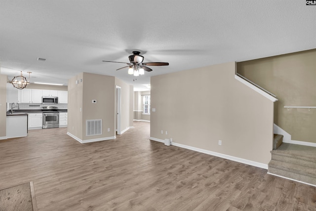 103 Beacon Ln, Columbia, SC 29229 - unfurnished living room with light wood finished floors, a ceiling fan, stairs, baseboards, and a chandelier
