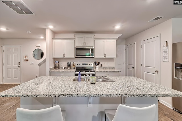 2040 Elmridge Rd, Columbia, SC 29209 - kitchen featuring stainless steel appliances, light wood-type flooring, a kitchen bar, light stone counters, and recessed lighting