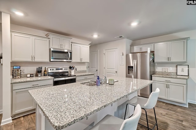 2040 Elmridge Rd, Columbia, SC 29209 - kitchen with stainless steel appliances, a sink, a breakfast bar, wood finished floors, and a center island with sink
