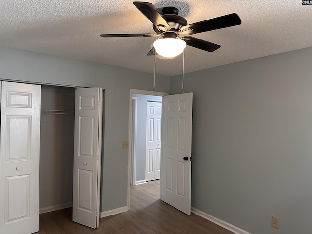 unfurnished bedroom with wood finished floors, baseboards, a textured ceiling, a closet, and ceiling fan