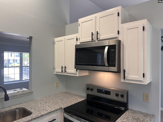 kitchen featuring stainless steel appliances, white cabinets, a sink, light stone counters, and crown molding
