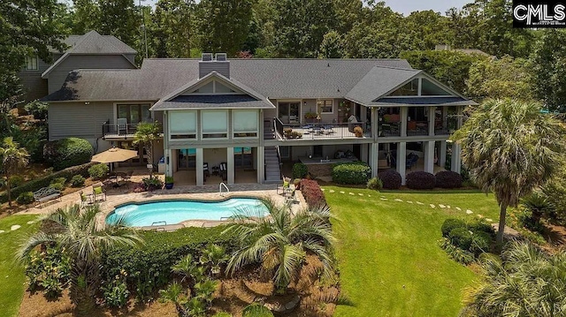 rear view of property with a balcony, a patio area, a yard, and an outdoor pool