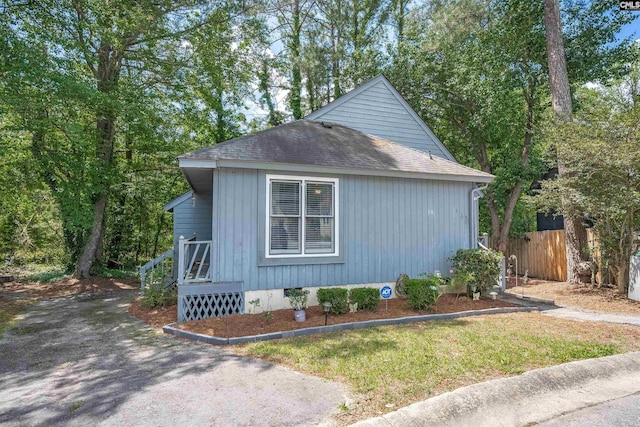 view of property exterior with fence and a shingled roof