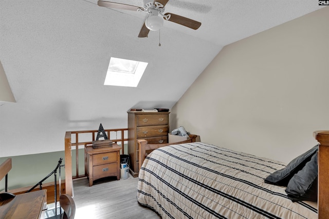 bedroom with a skylight, wood finished floors, lofted ceiling, and a textured ceiling