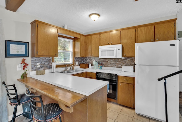 kitchen featuring white appliances, a sink, light countertops, decorative backsplash, and a peninsula