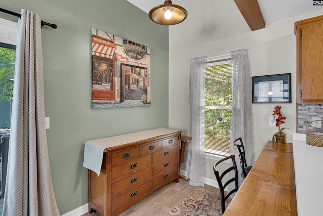 office space with plenty of natural light, baseboards, light wood-style floors, and beam ceiling