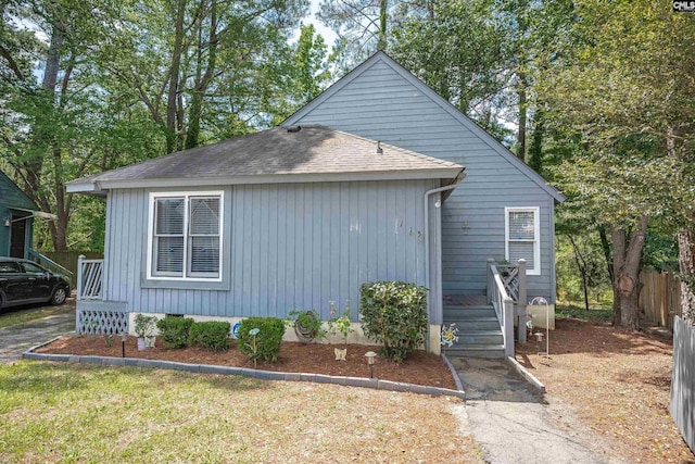view of front of property with roof with shingles and fence
