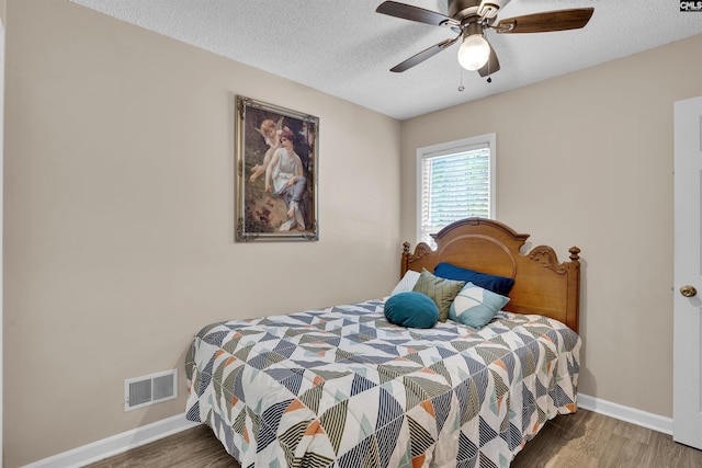 bedroom featuring wood finished floors, a textured ceiling, baseboards, and ceiling fan