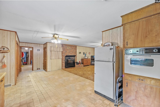 kitchen featuring white appliances, a ceiling fan, and wood walls