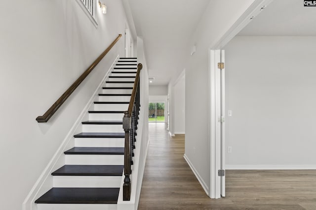stairway with wood finished floors and baseboards