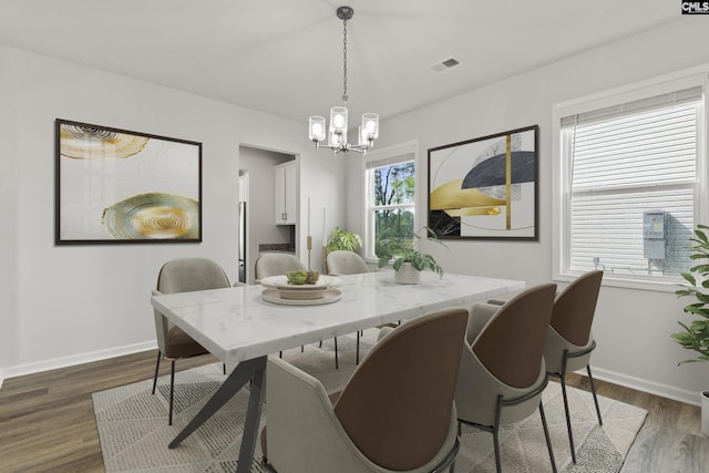dining space featuring a chandelier, dark wood-type flooring, and baseboards