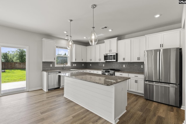 kitchen with stainless steel appliances, a sink, backsplash, white cabinetry, and dark wood-style flooring