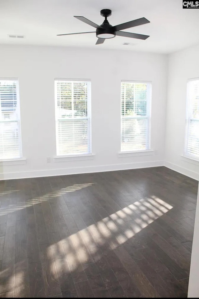 spare room featuring a ceiling fan, baseboards, wood finished floors, and healthy amount of natural light