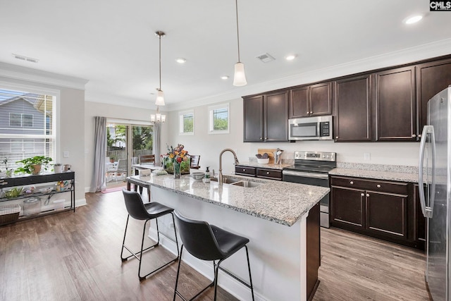 kitchen with stainless steel appliances, a sink, light wood-style flooring, dark brown cabinets, and crown molding