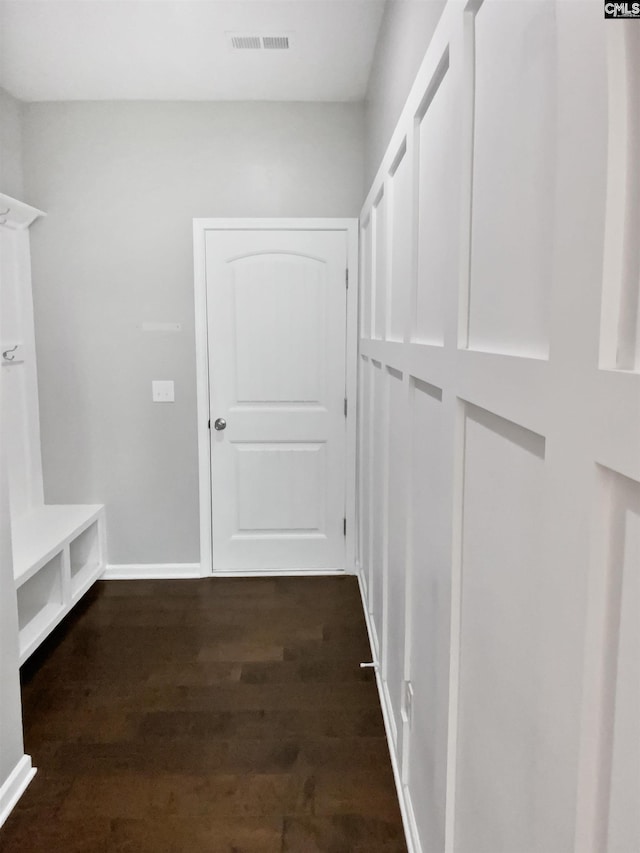 mudroom with dark wood finished floors and baseboards